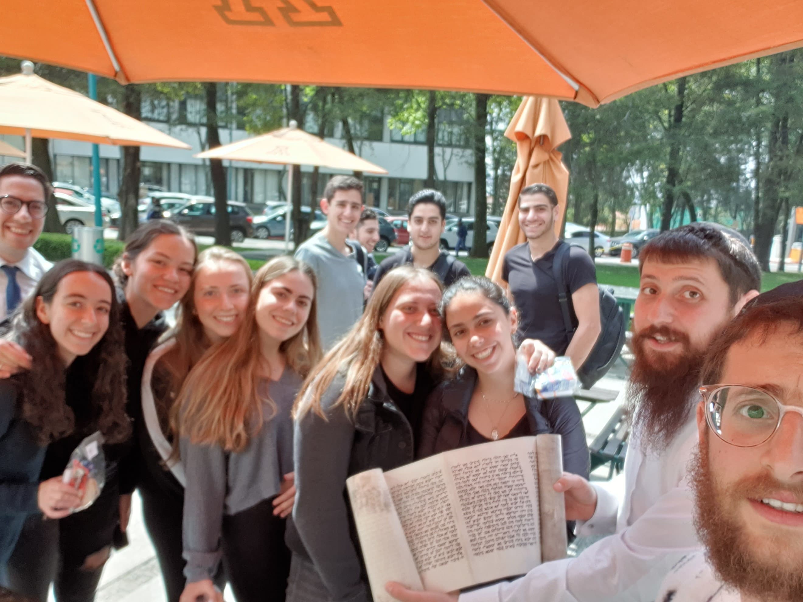 El rabino y un grupo de estudiantes con un rollo de Torá en el campus